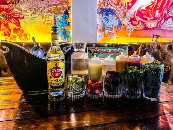 in the foreground a bottle of Havana club with a collection of mixers limes and ingredients for a Mojito. set against the vibrant walls of Castro's bar newcastle.