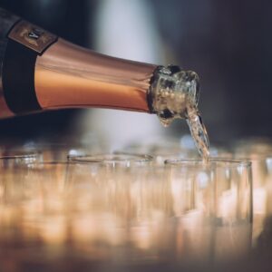 Prosecco pouring from a gold topped bottle into champagne glasses.