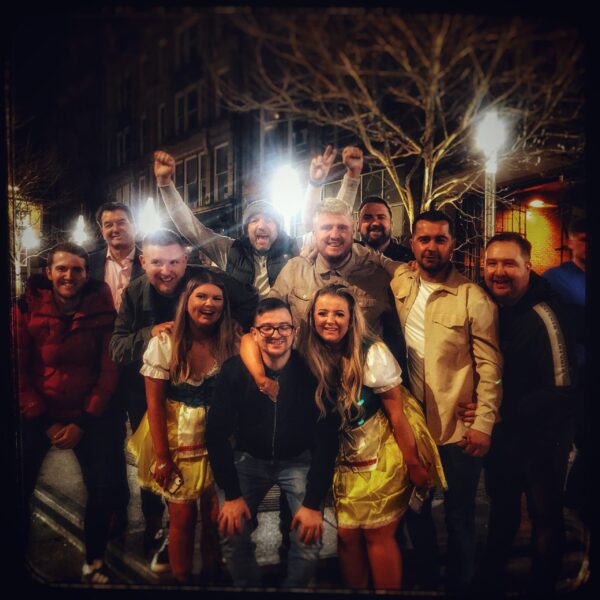 a group of men on a stag weekend in Newcastle's Bigg market , with two gorgeous girls in bavarian outfits in the middle.