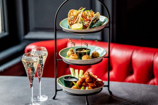 metal tower with three plates of brunch dishes next to two full glasses of bubbly